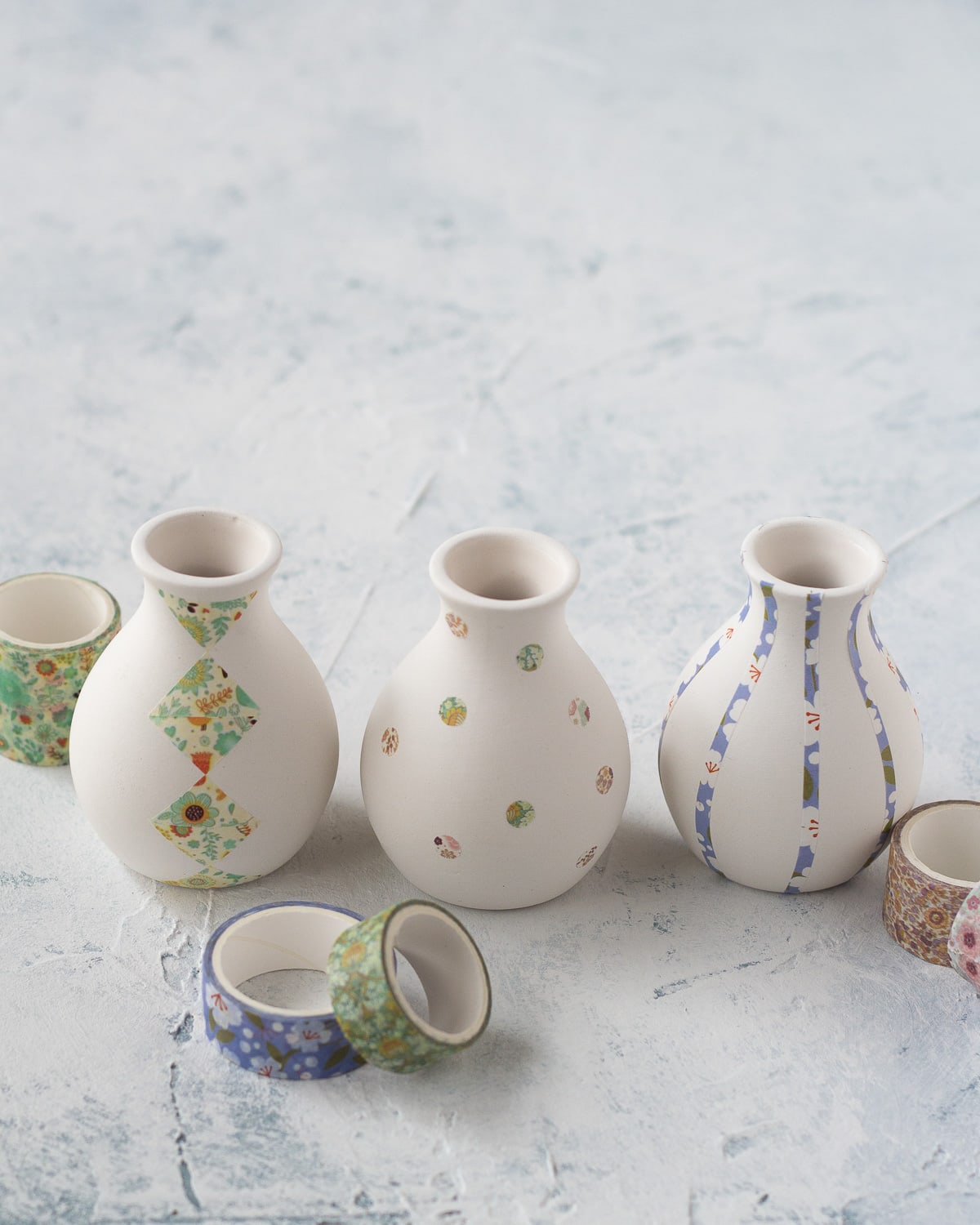 Three small ceramic bud vases decorated with washi tape.