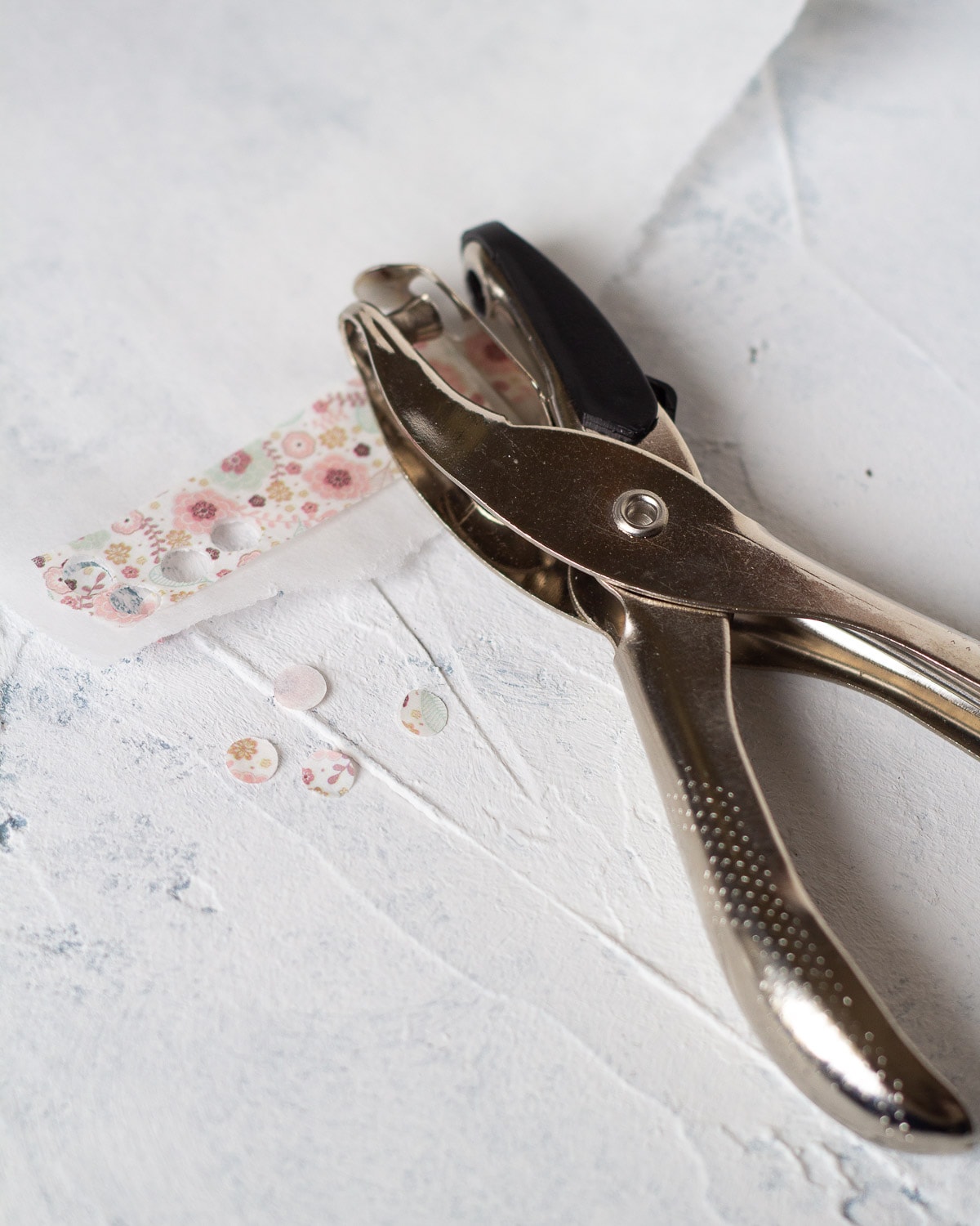 Using parchment paper and a hole punch to punch circles of washi tape for decoration.