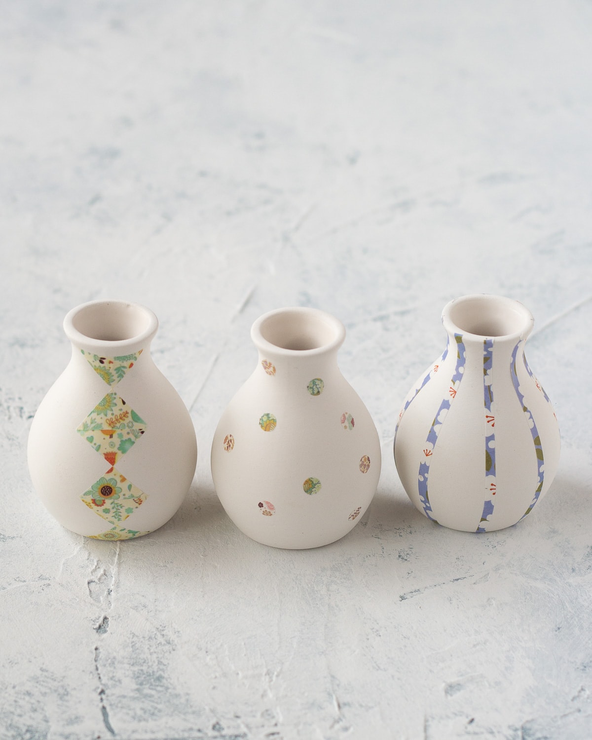 Three small ceramic bud vases decorated with washi tape.