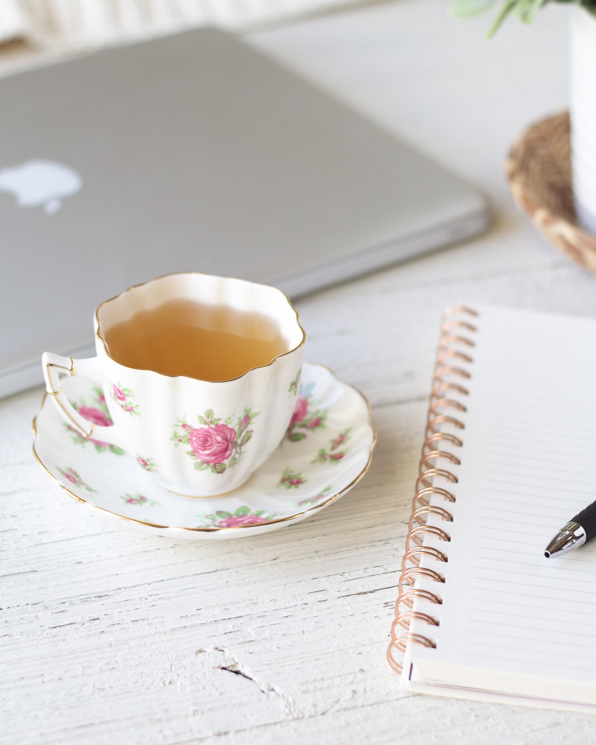 A teacup and notebook on a wooden surface.