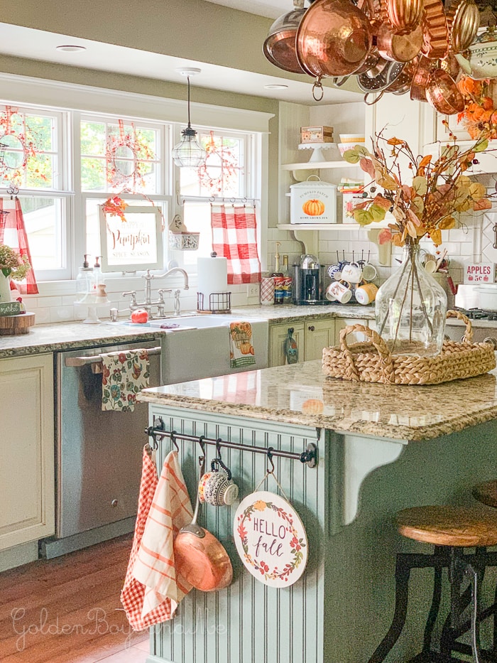 A cottage kitchen with blue/green island and colorful fall décor.