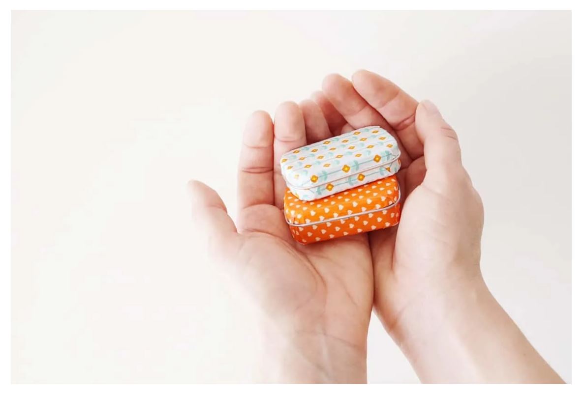 Hands holding two mint tins that have been decorated with washi tape.