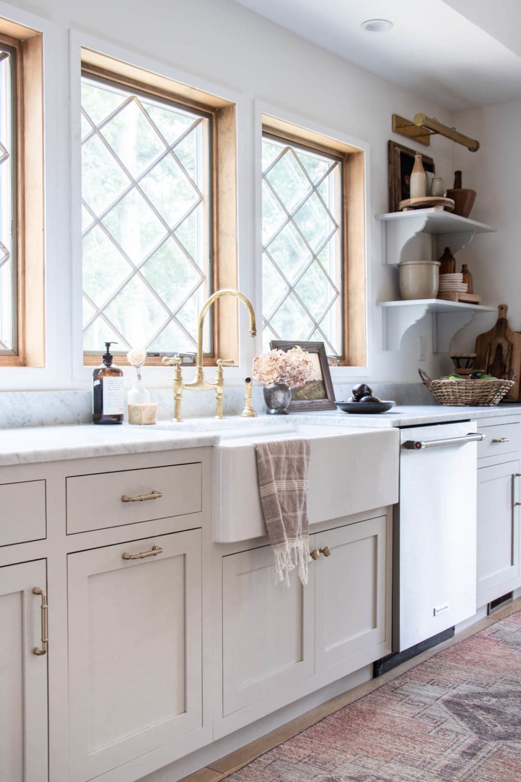 An apron sink with neutral cabinets and diamond pane windows.