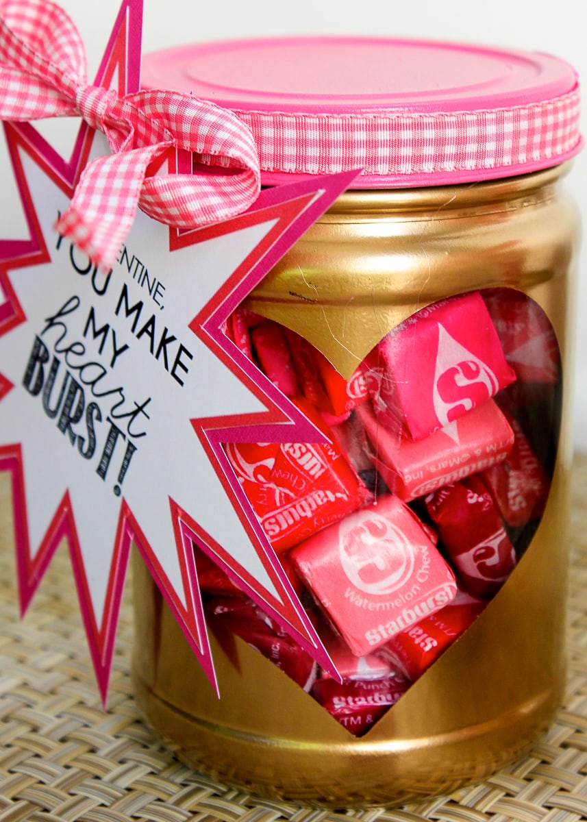 A jar painted gold with a heart cutout revealing that it is filled with candy.