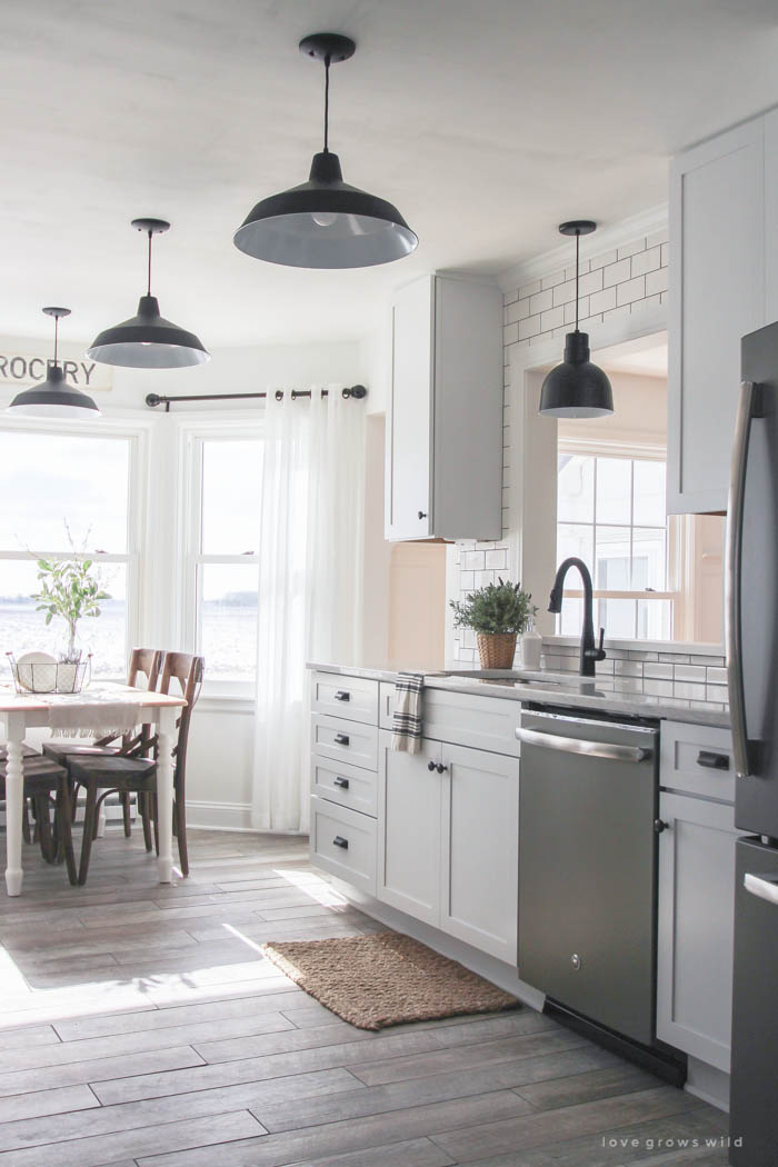 Farmhouse style kitchen with white cabinets and black light fixtures.