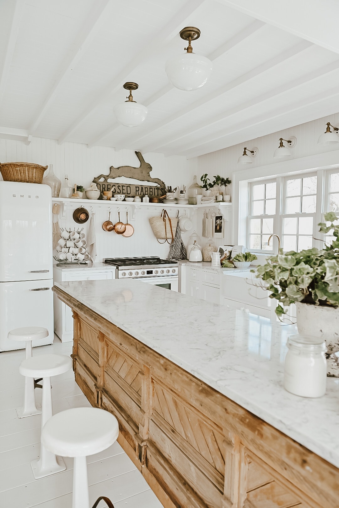 A white farmhouse style kitchen with an antique countertop island.