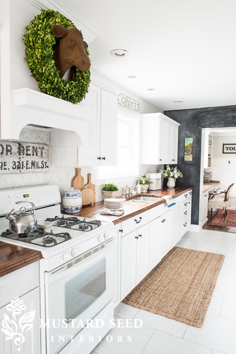 Miss Mustard Seed's first kitchen with painted white cabinets and dark butcher block countertops.