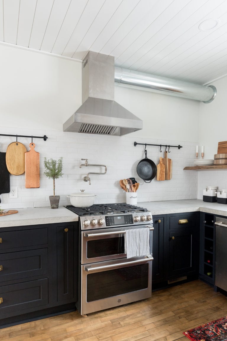 A farmhouse style kitchen with black cabinets and wood floors.