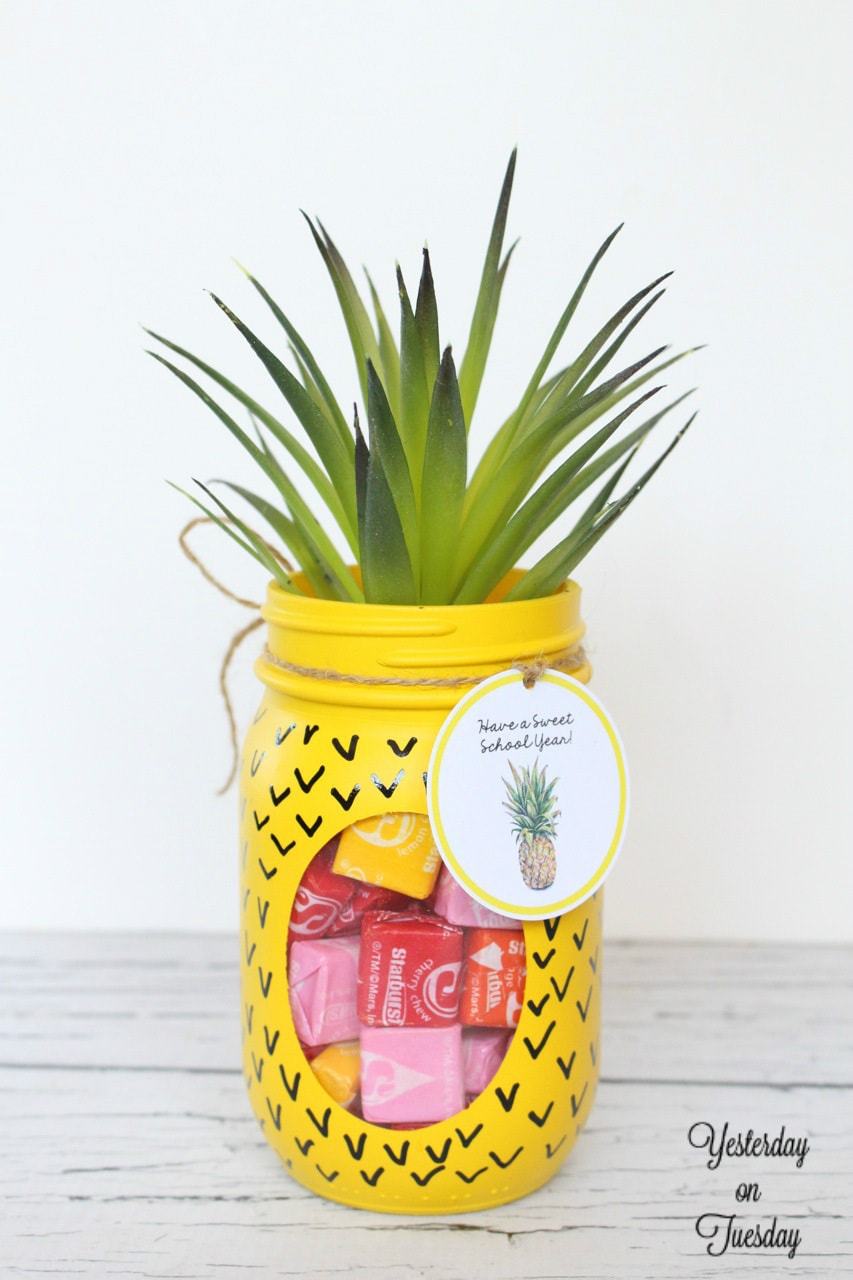 A mason jar turned into a pineapple with yellow paint and faux succulent on top.