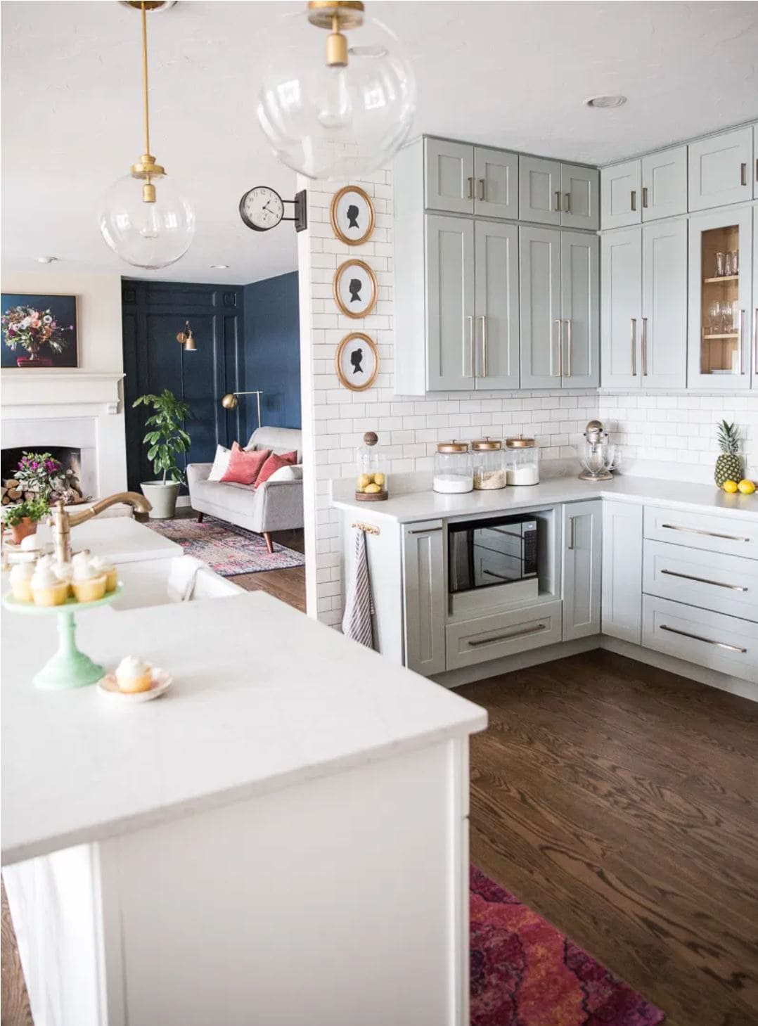 A modern kitchen design with green-gray cabinets and gold accents.