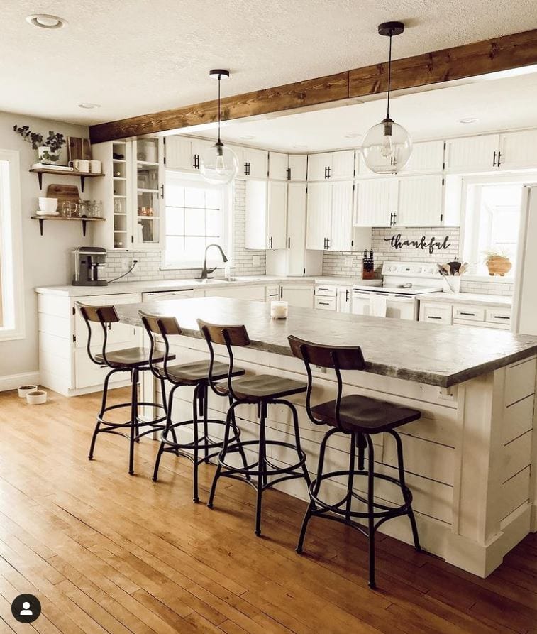 A rustic farmhouse kitchen with a big shiplap island and bar stools.
