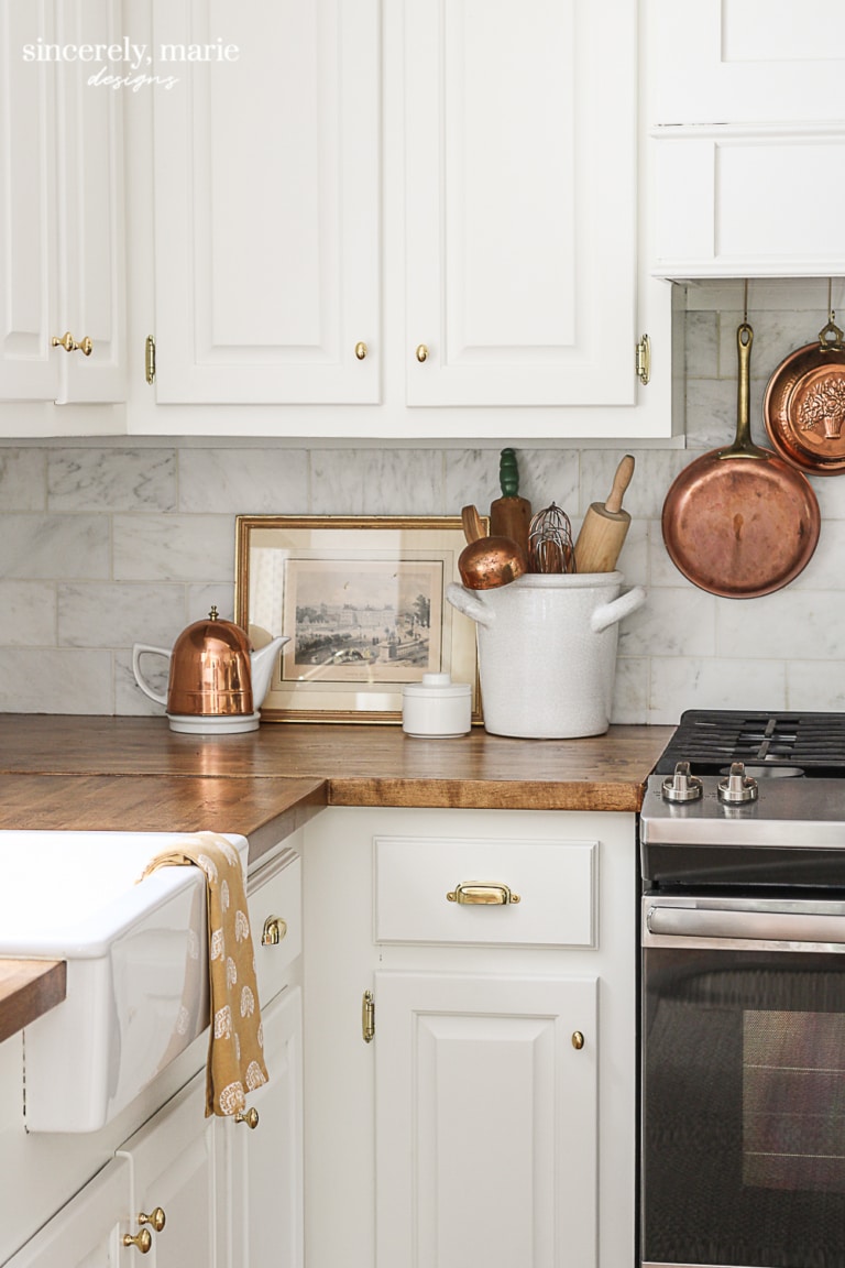 Warm white cabinets with gold hardware and copper accents.