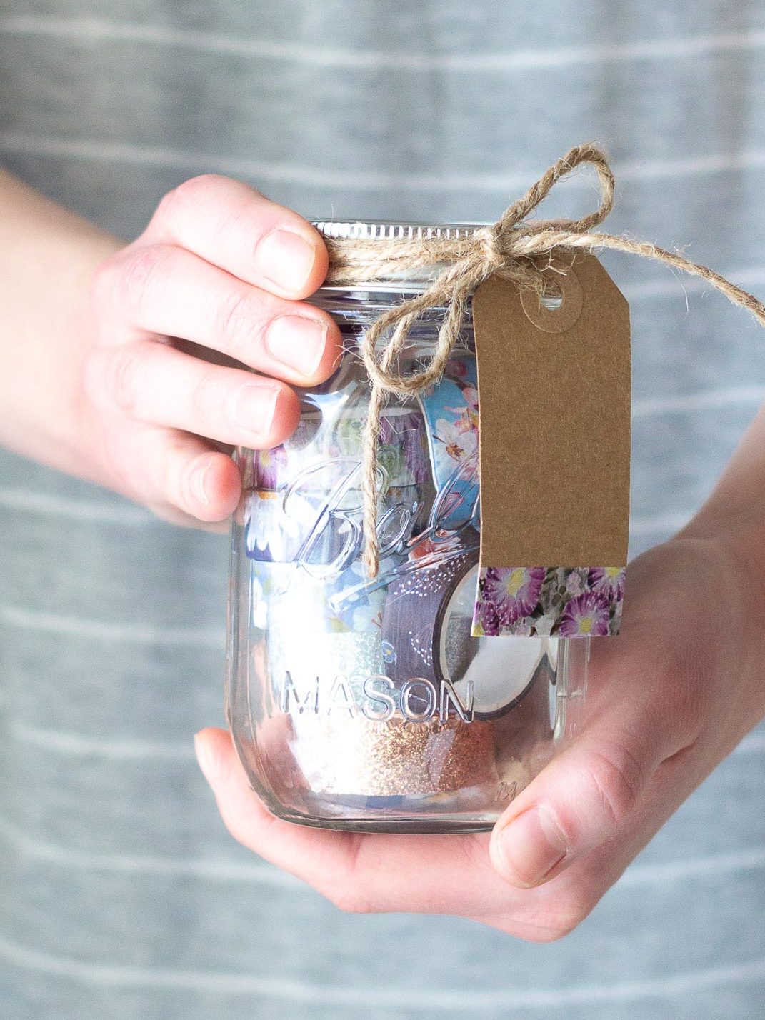 Holding a Washi Tape Mason Jar Gift Idea filled with colorful washi tape.