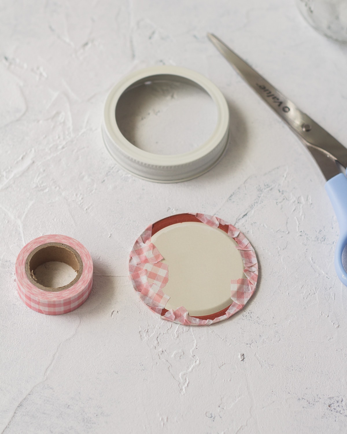 Wrapping a mason jar lid with tape.