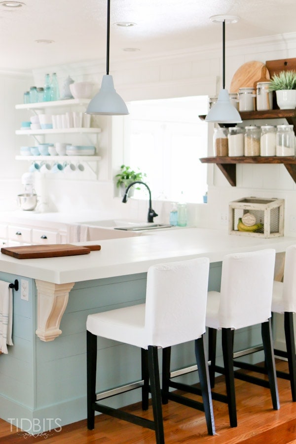 A kitchen with a bright blue/green island and decorative corbels.