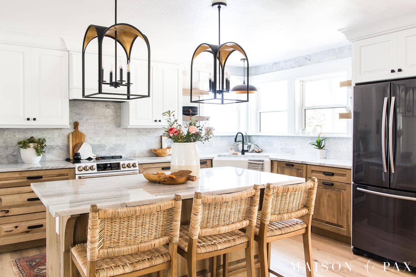 A stunning white and wood kitchen with wood cabinets, a white apron sink and statement light fixtures.