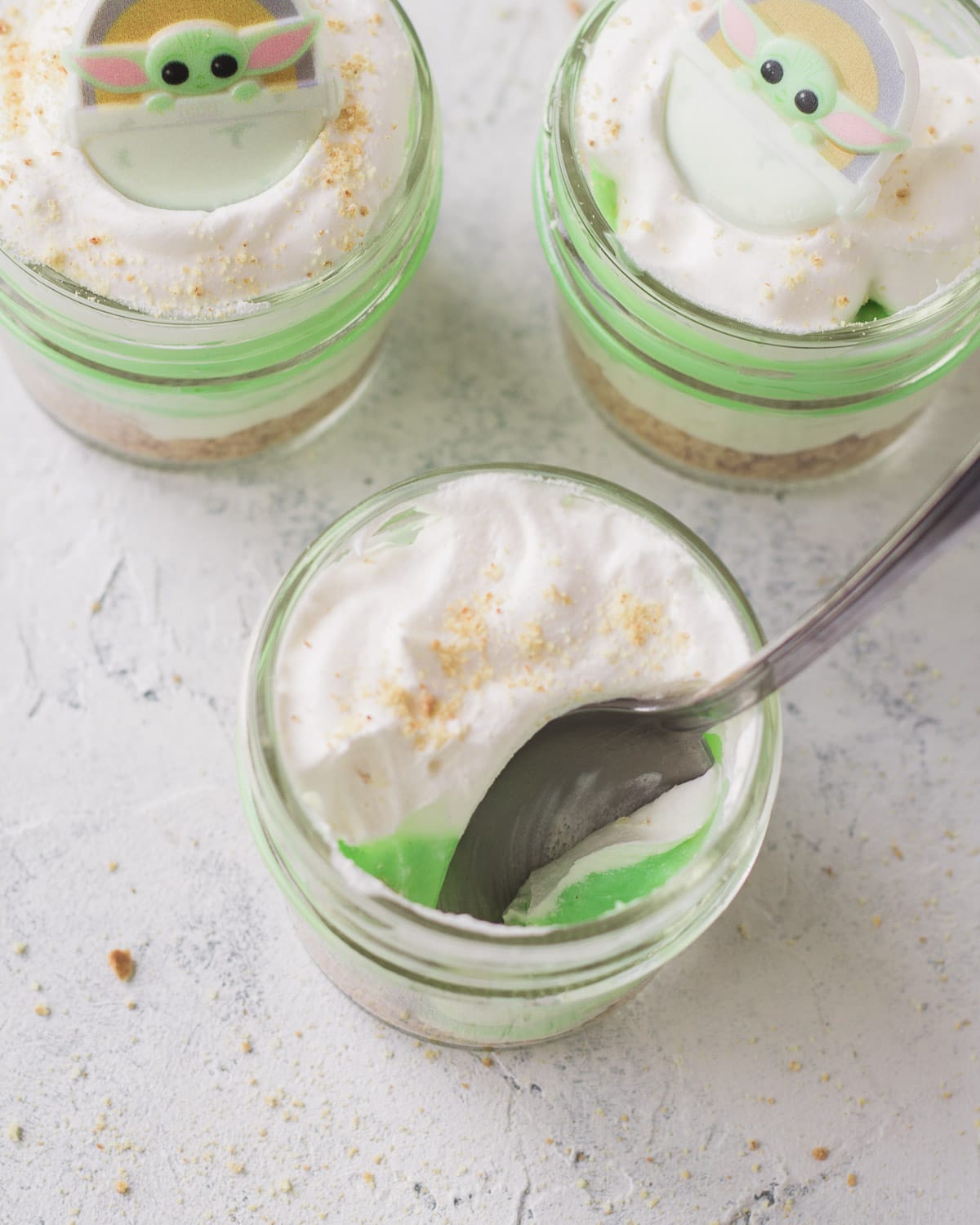 A spoon removing a bite from a pistachio pudding mini mason jar dessert.