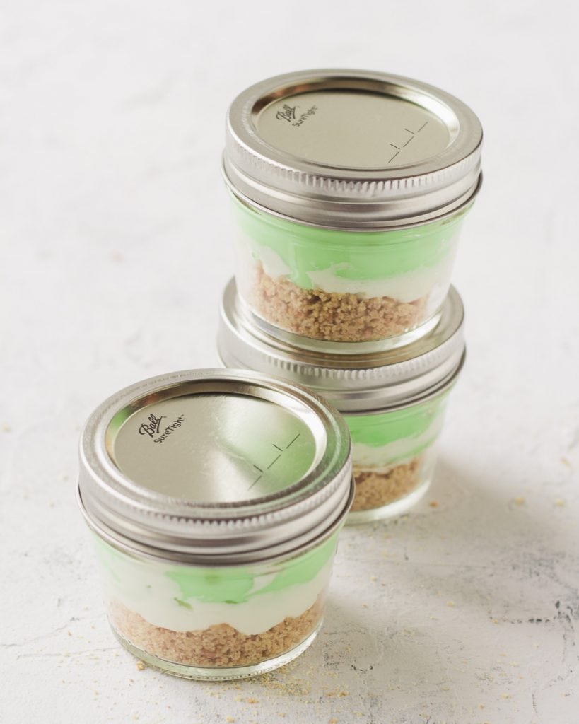 Three mason jar desserts with the lids on for travel.