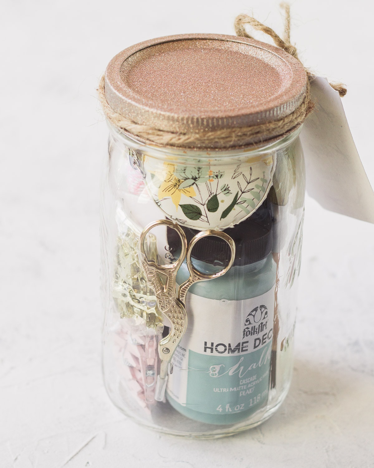 Embroidery scissors, chalk paint, and various craft supplies in a mason jar.