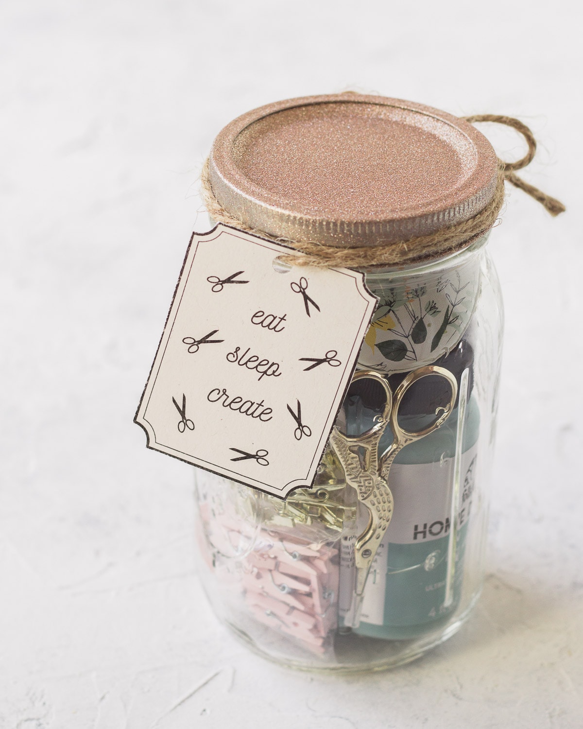 A craft supplies mason jar with a handmade gift tag.