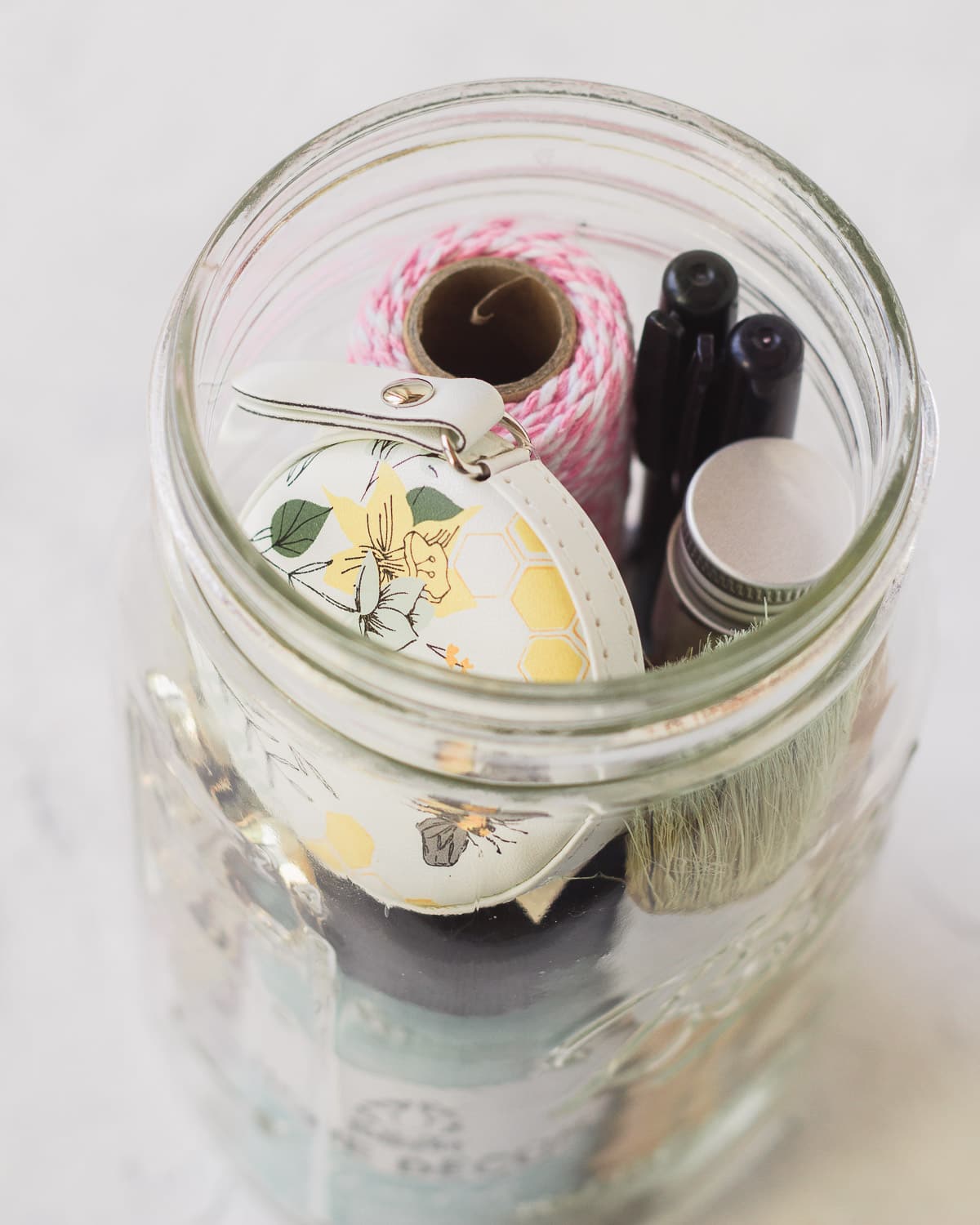 A tape measure and craft supplies packed into a mason jar.