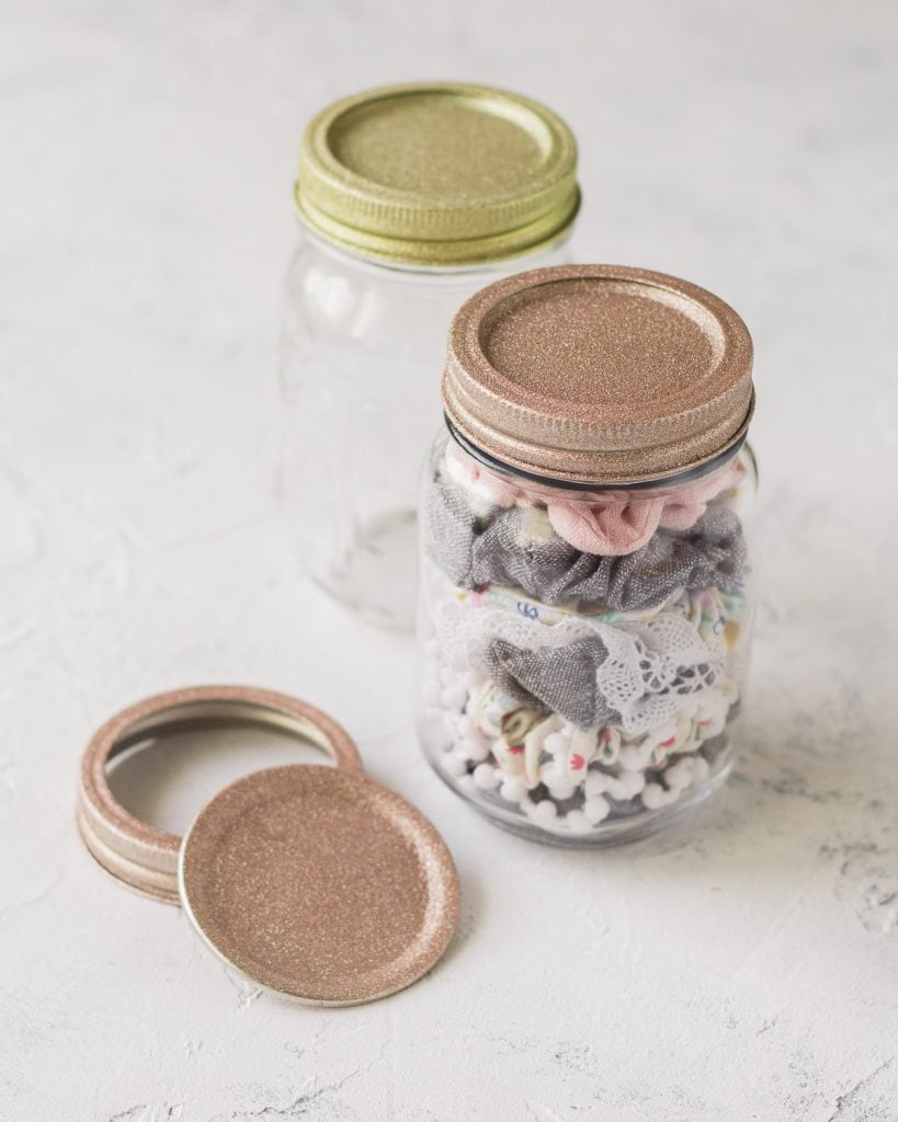 Glass jar filled with scrunchies and a glitter-covered lid.