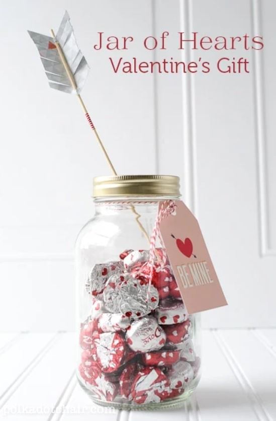 A mason jar filled with heart candies and a printed arrow.