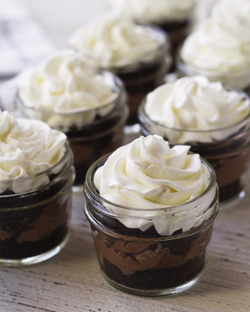 Chocolate desserts-in-a-jar topped with homemade whipped cream.