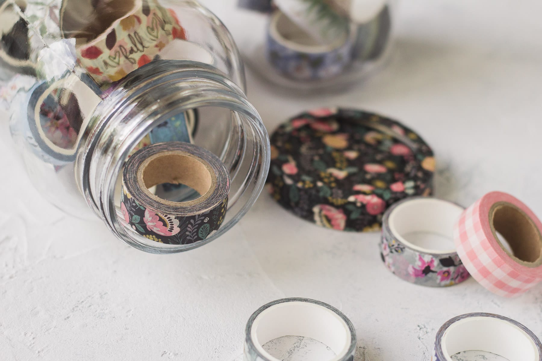 Washi tape in a mason jar with more spools surrounding.