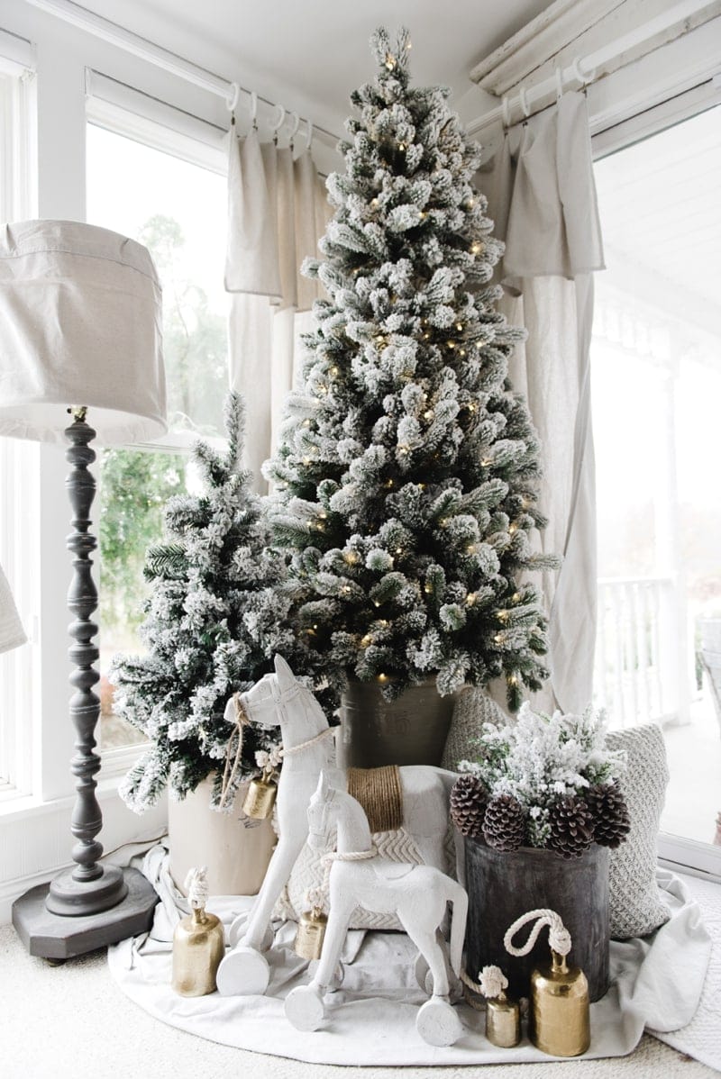 Chalk-painted white rocking horses in front of a flocked Christmas tree.