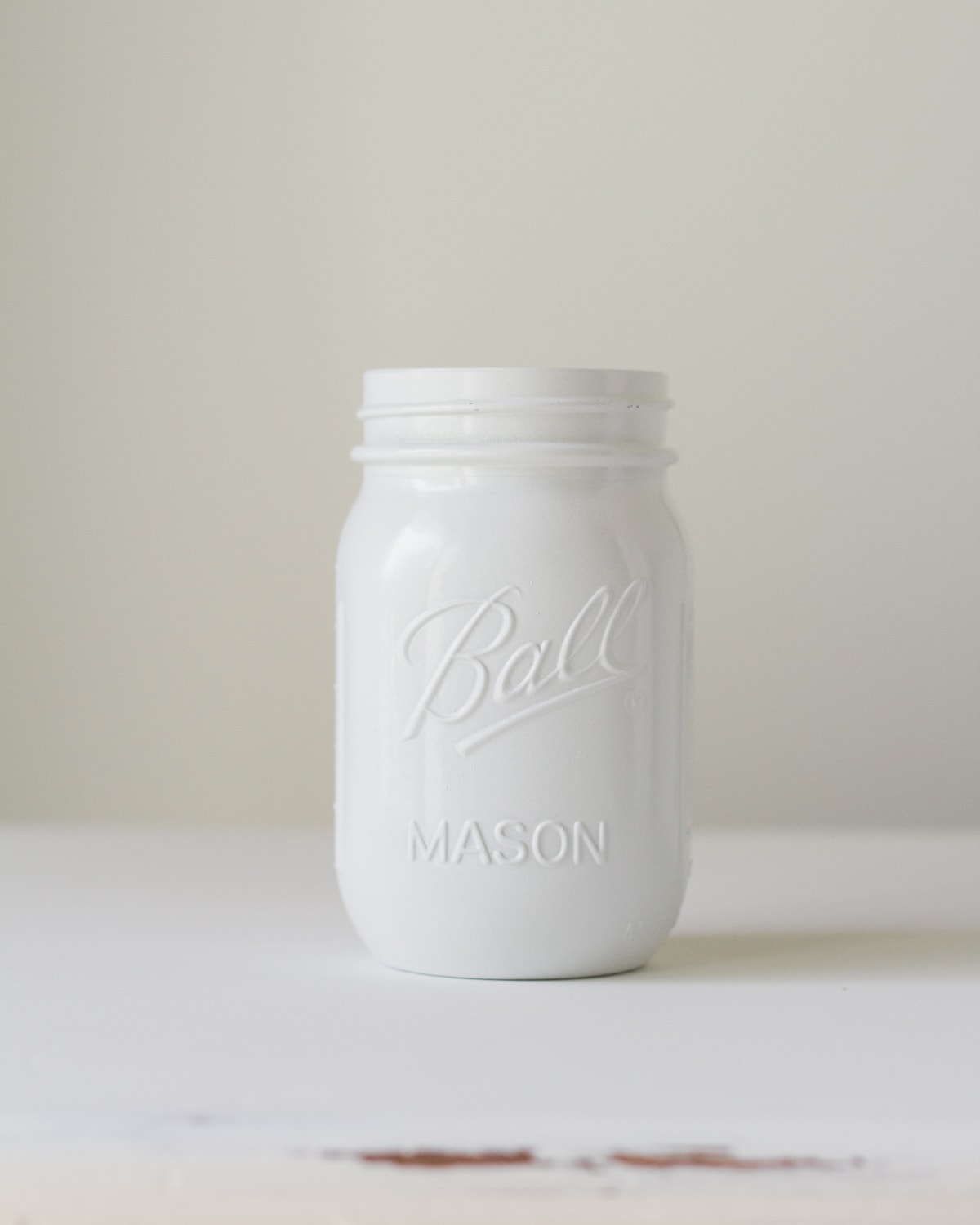 A Ball Mason Jar painted with glossy white spray paint.