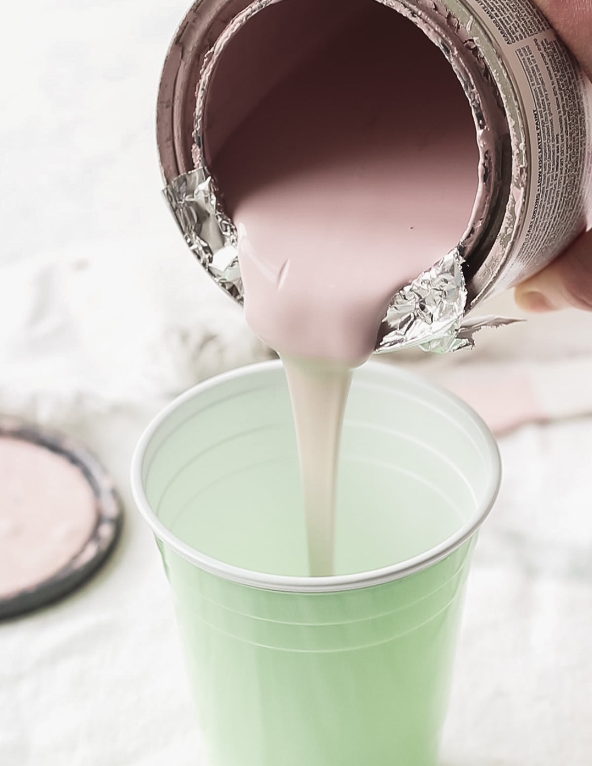 Pouring chalk paint into a disposable cup.