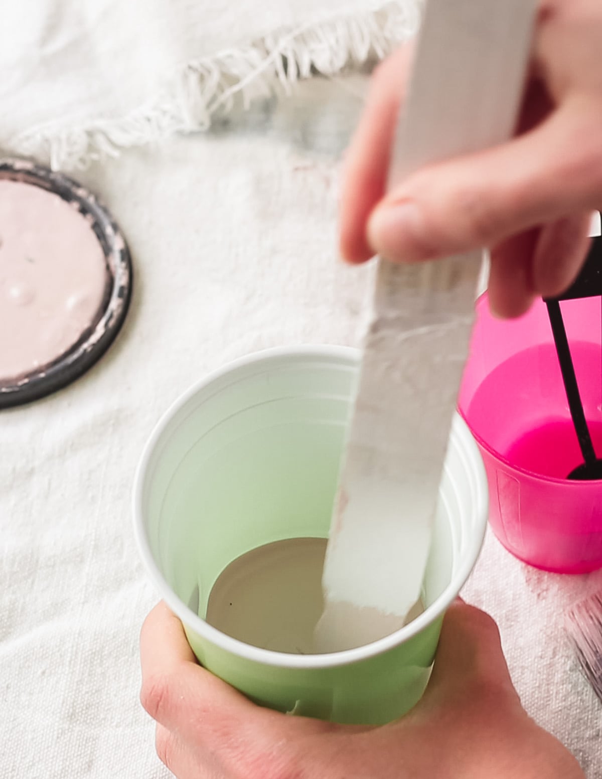 Stirring chalk paint in a disposable cup.