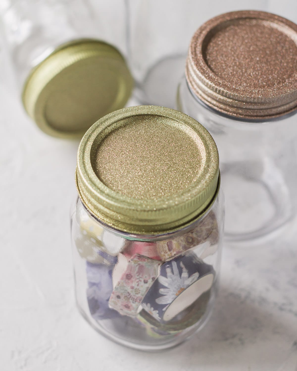 Mason jars topped with glittery lids in gold and rose gold.