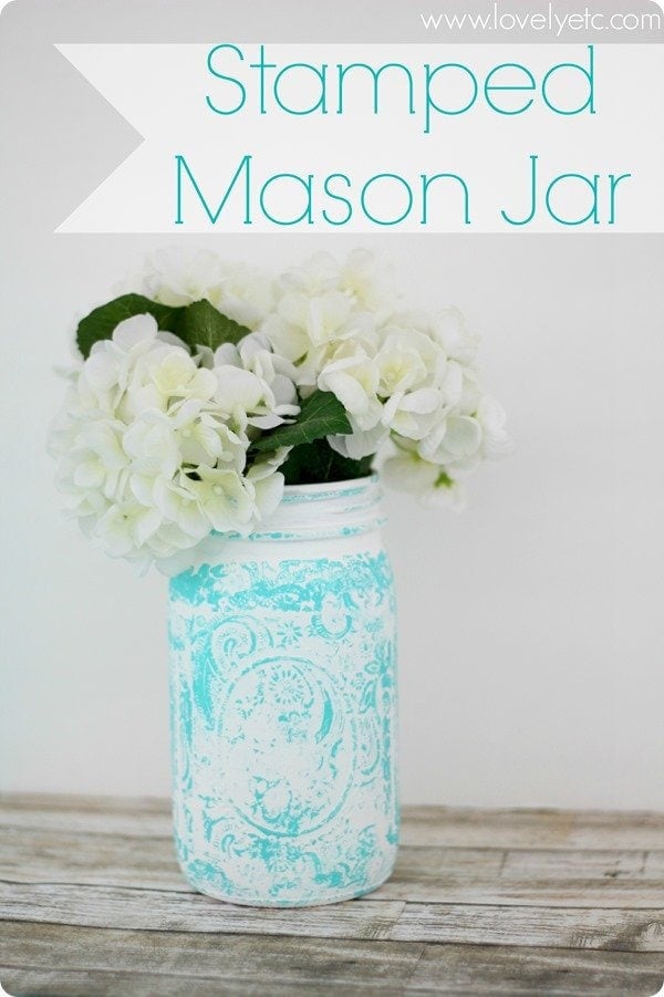 A turquoise stamped mason jar with flowers inside.