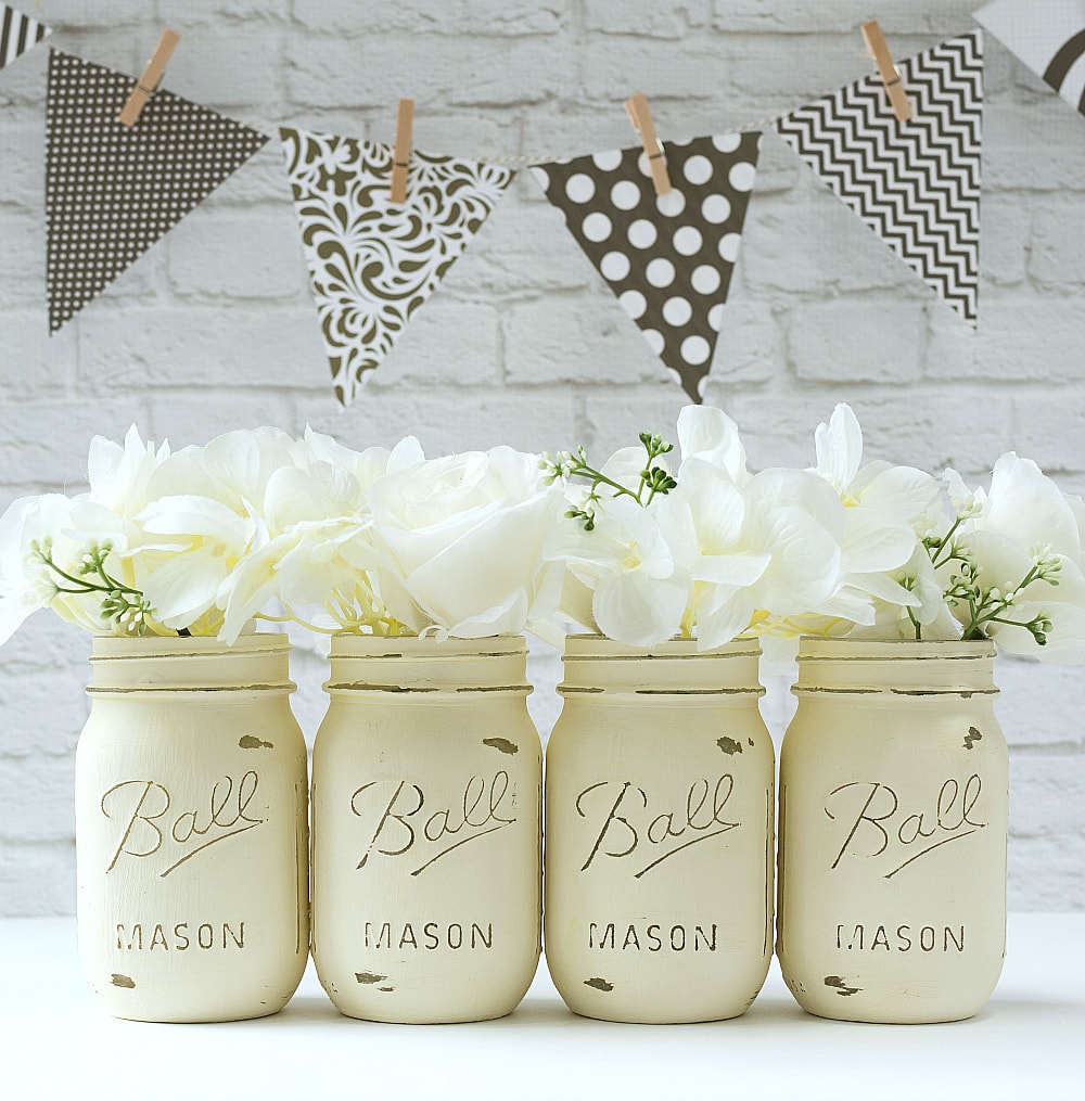 Four mason jars painted with cream-colored chalk paint.