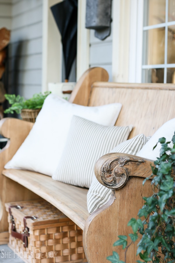 A vintage church pew on a porch with pillows.