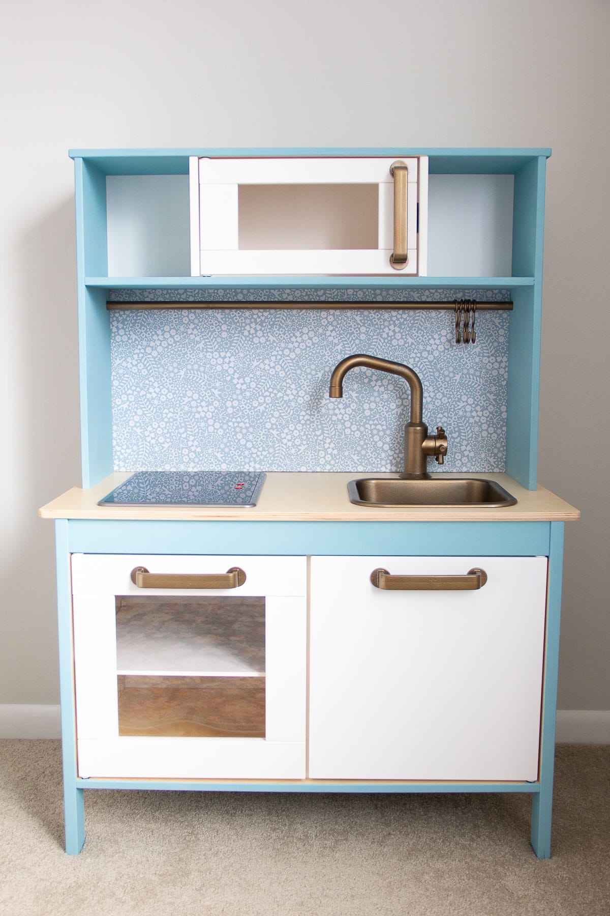 An IKEA play kitchen hack painted with blue chalk style paint.
