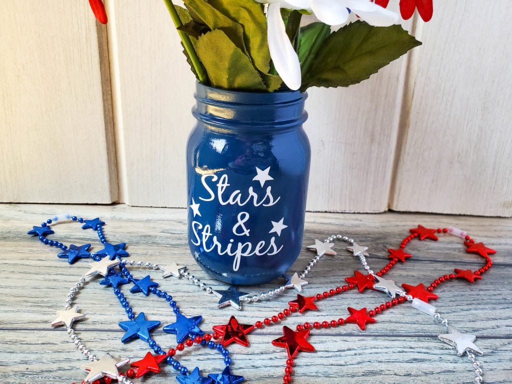 A blue "stars and stripes" mason jar made with a Cricut.