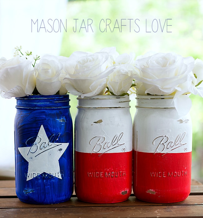 Mason jars filled with white flowers and painted to resemble a Texas flag.