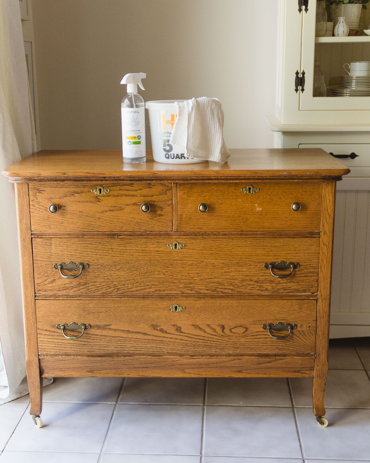 A vintage oak dresser with cleaning supplies on top of it.