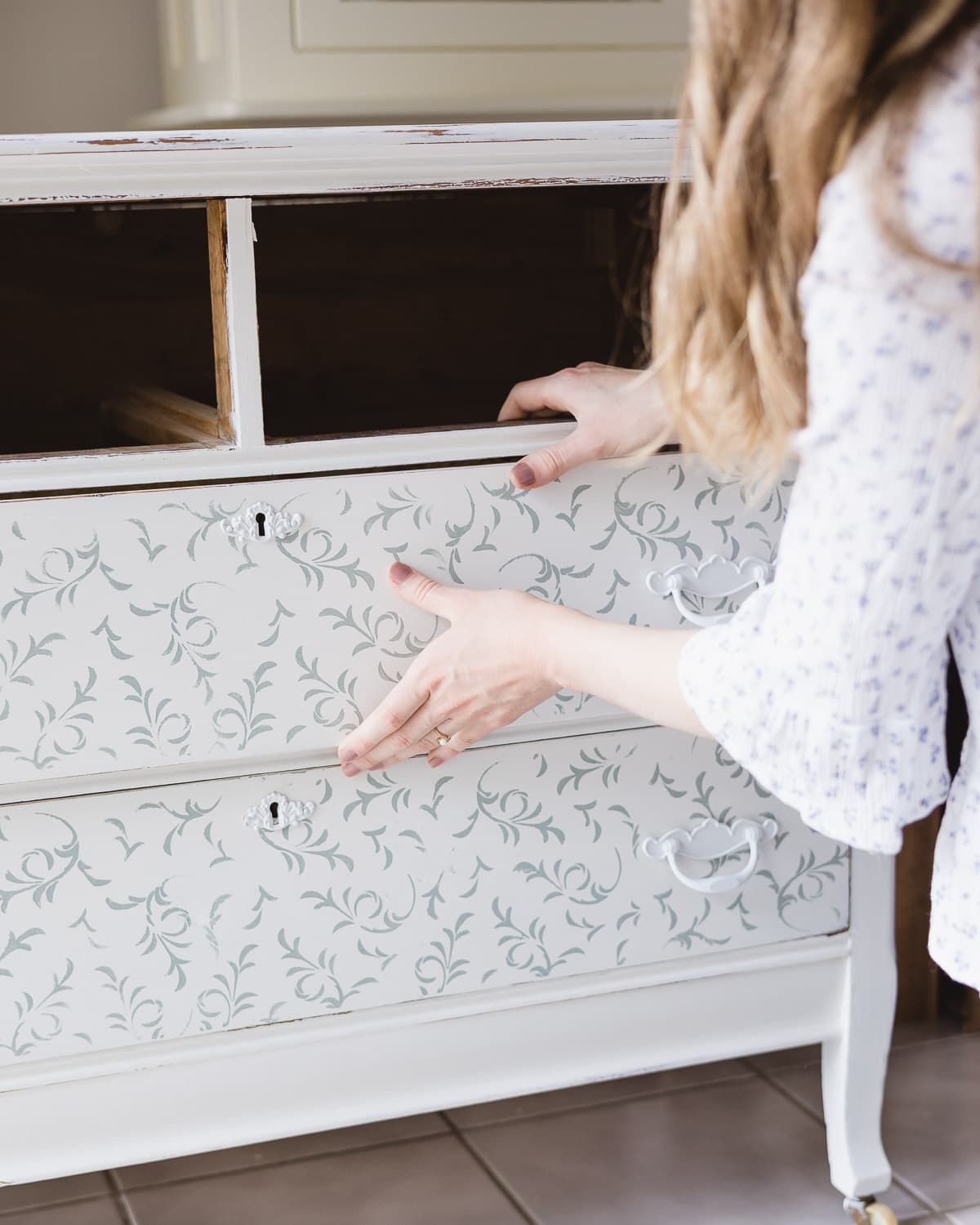 Inserting a drawer back into a painted dresser.