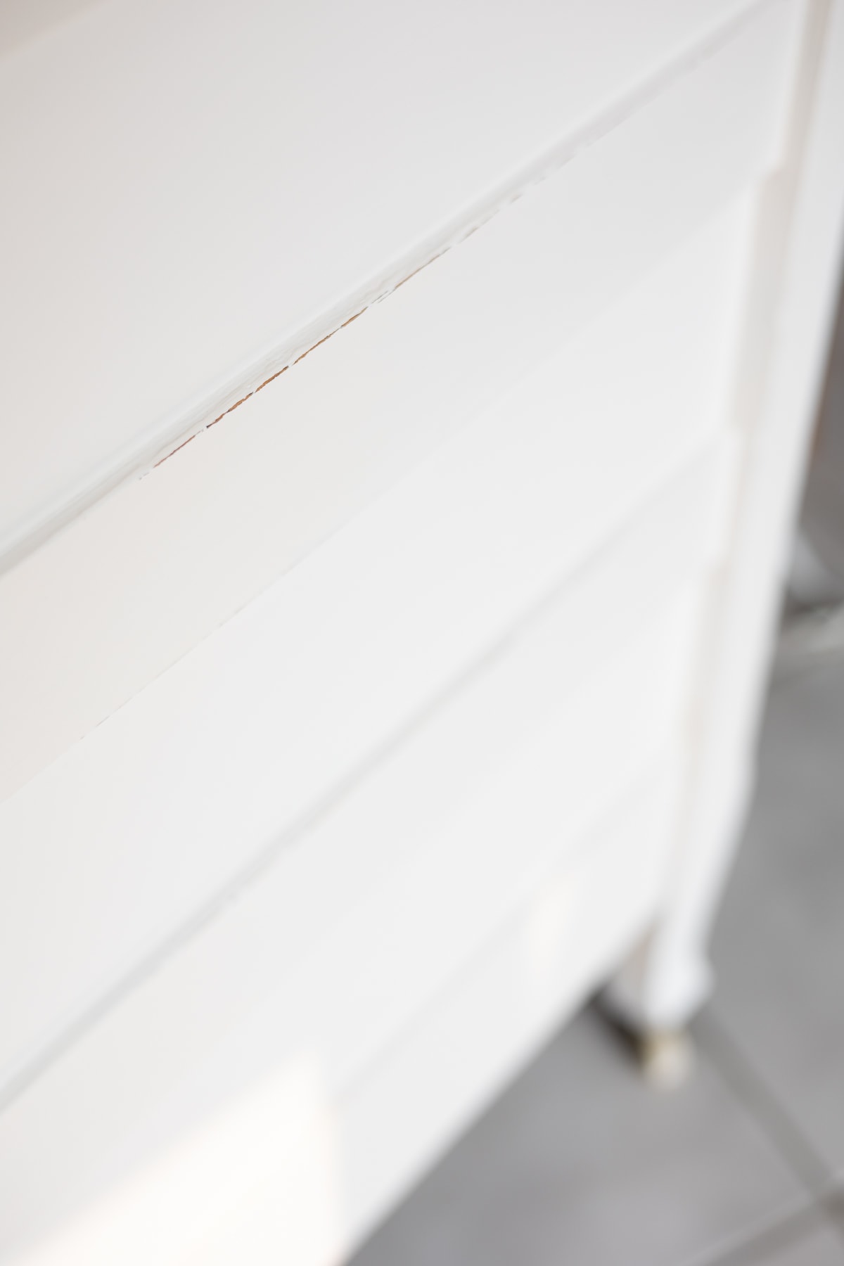 The side of a white dresser showing the difference between a waxed and an unwaxed finish.