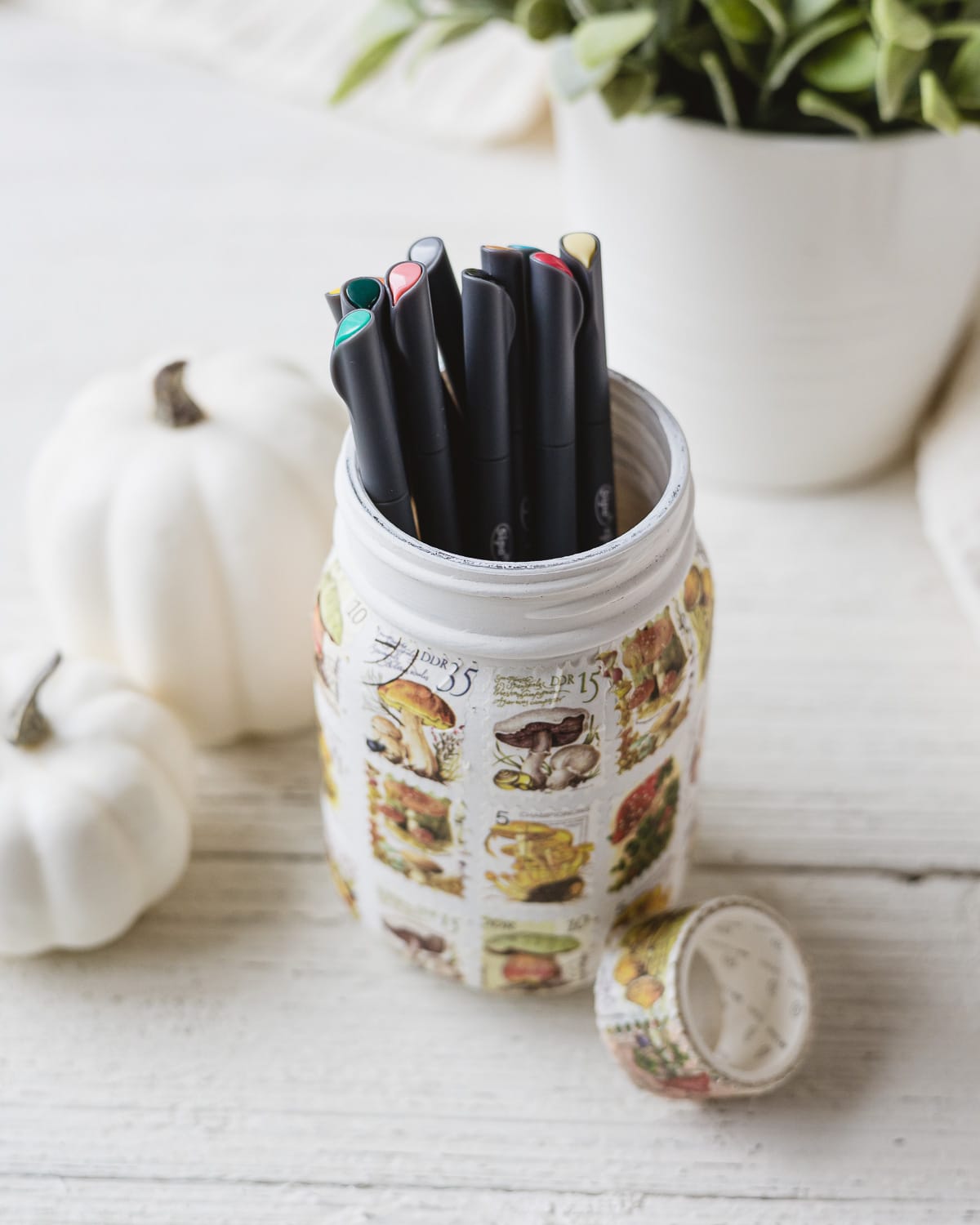 A mason jar pencil holder with colored markers inside.