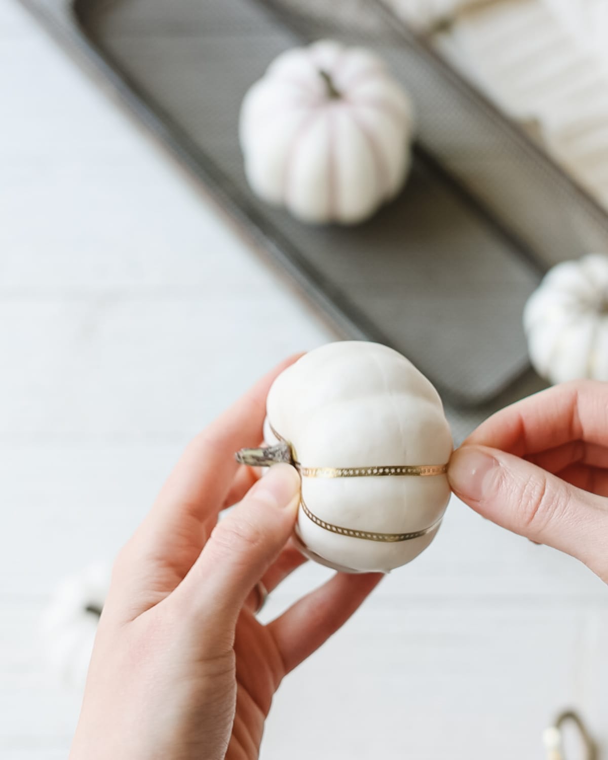 Wrapping gold washi tape around a white foam pumpkin.