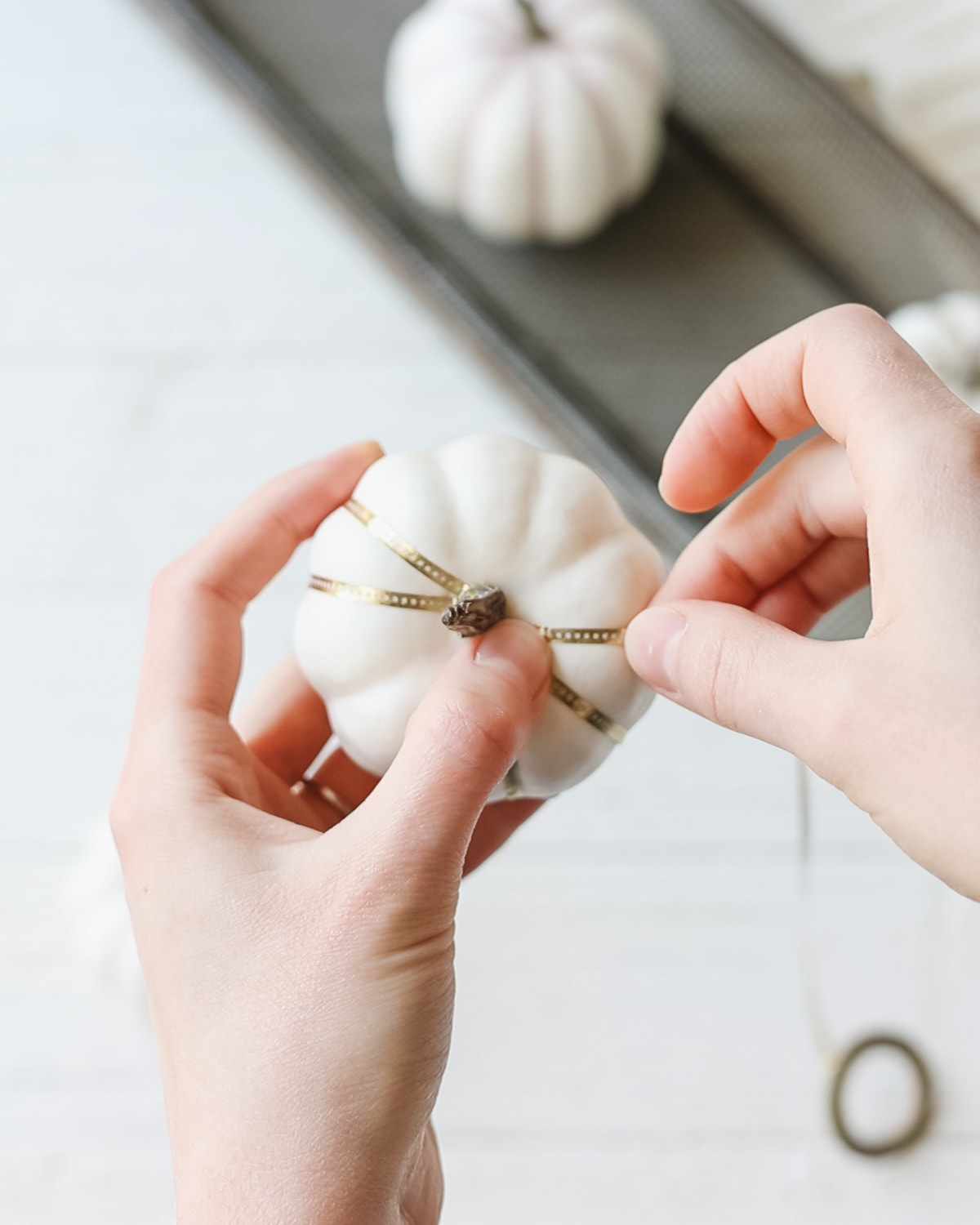 Wrapping gold washi tape around a white foam pumpkin.