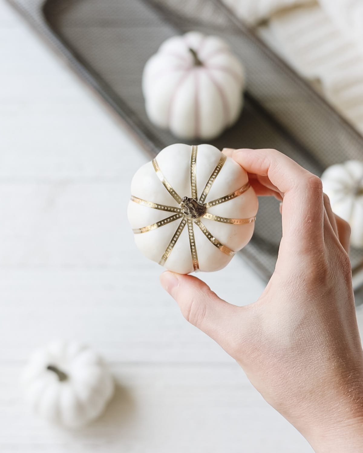 A small white home décor pumpkin decorated with gold washi tape.