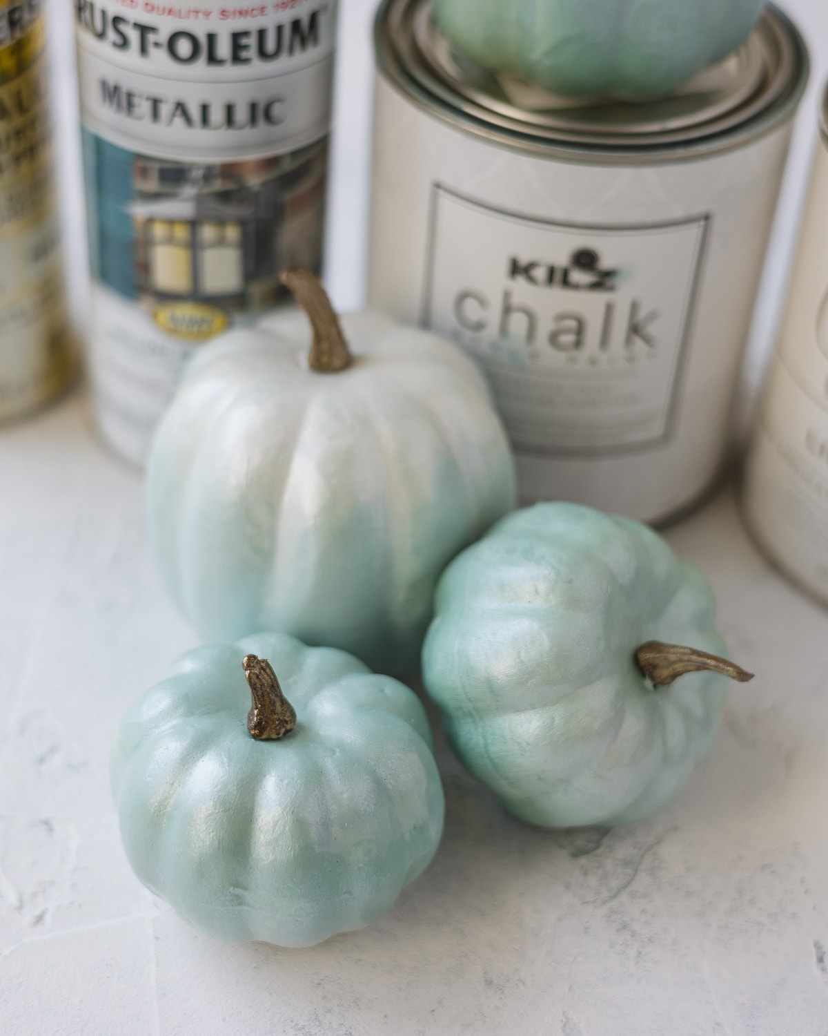Chalk painted pumpkins with chalk paint cans in the background.
