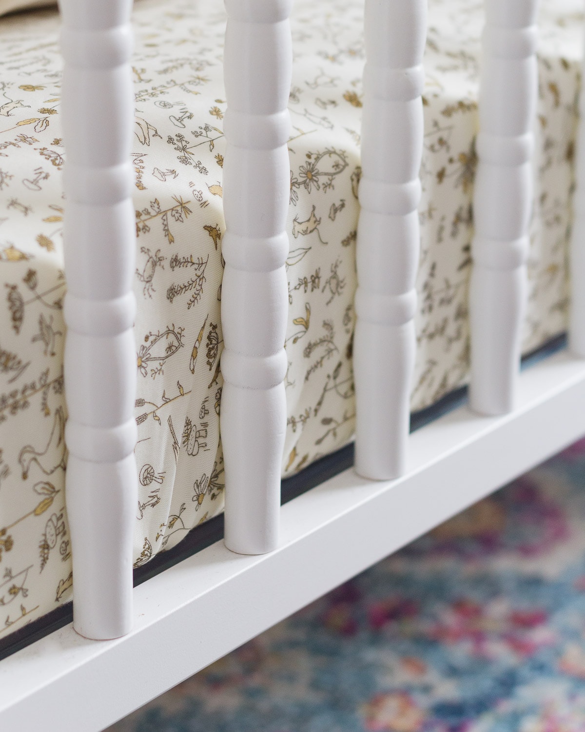 A white Jenny Lind Crib with a crib mattress inside.