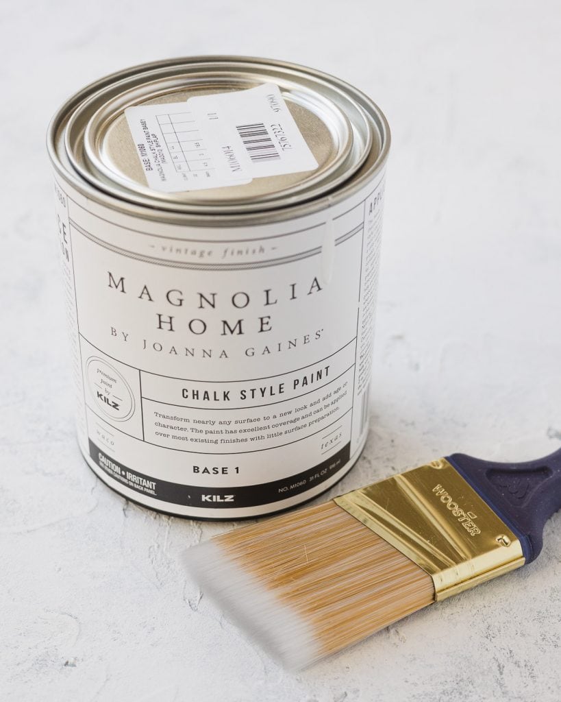 A can of Magnolia Home Chalk Paint by Joanna Gaines and a small paintbrush.